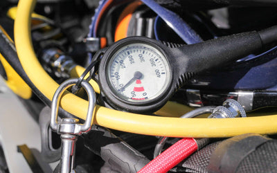 A close-up of a scuba diving pressure gauge and colorful hoses, representing essential gear for a dive travel adventure.