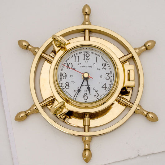 Nautical clock embedded in a polished brass ship’s wheel design, featuring a quartz face and 24-hour time display.